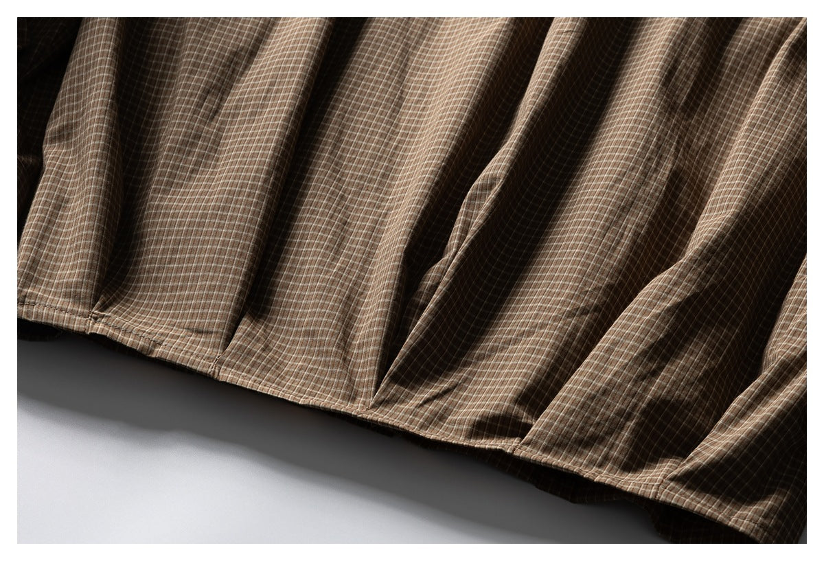 Close-up of the hem and stitched edge of a brown checked garment.
