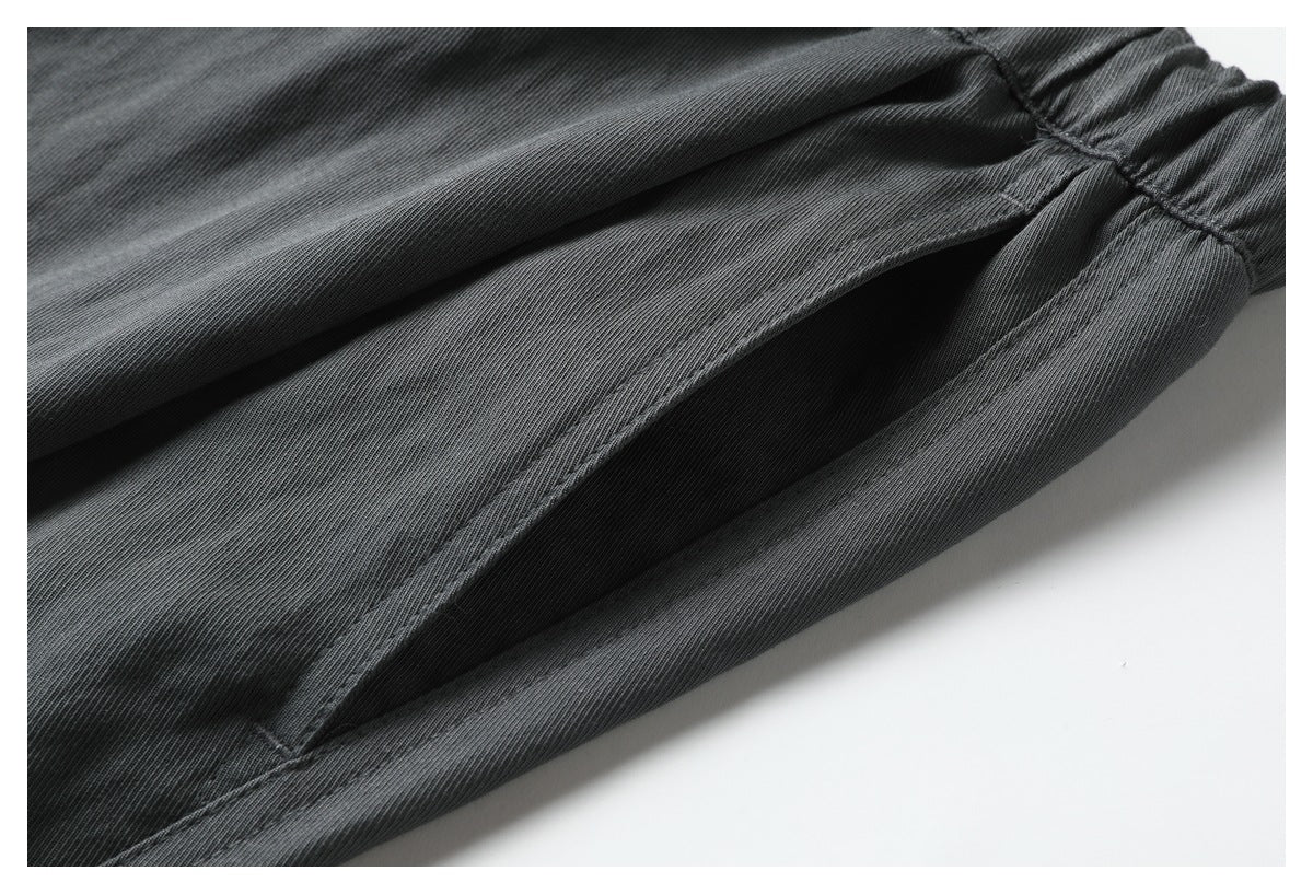 Close-up of a slanted side pocket and stitched seams on charcoal gray pants.
