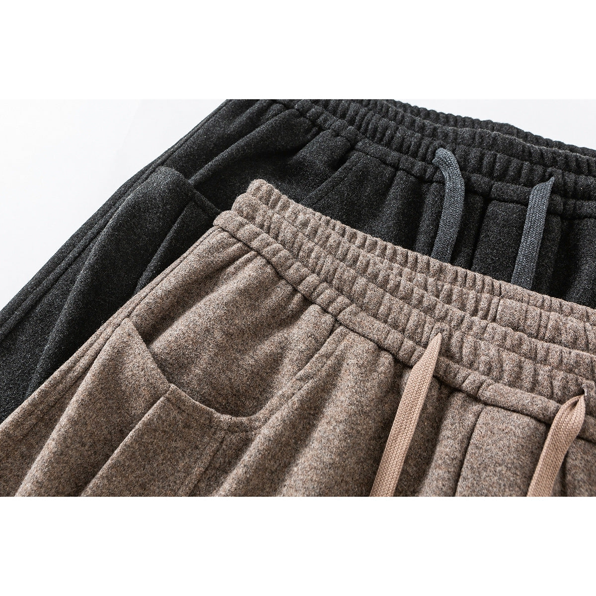 Close-up of charcoal and taupe wide-leg pants showing elastic waistbands, drawstrings and front pockets.