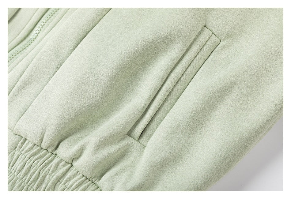 Close-up of pale sage-green garment showing a welt pocket and gathered elastic waistband.