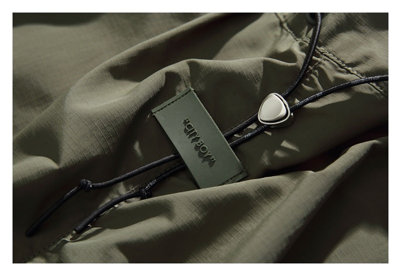 Close-up of the olive shorts' drawcord and attached CITY BOY tag against the fabric.