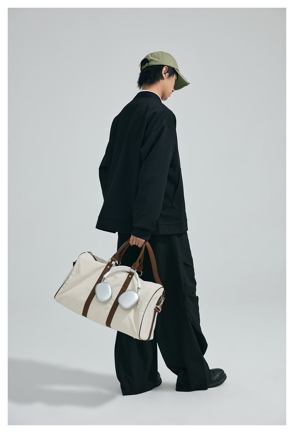 Model shown from the back wearing a black loose-fit jacket with ribbed cuffs and hem, paired with wide-leg trousers.