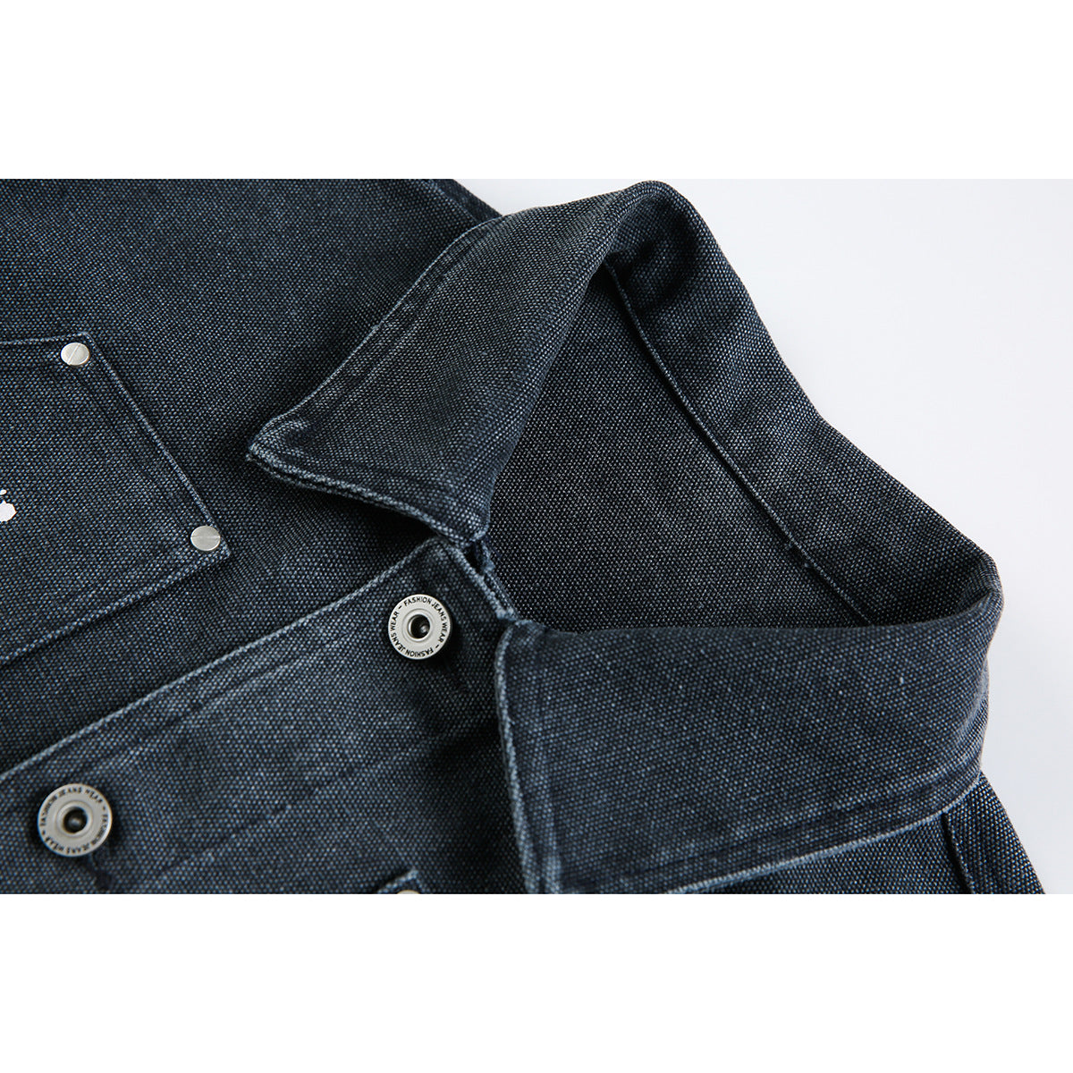 Close-up of a dark indigo textured jacket collar, seams, and silver snap buttons.