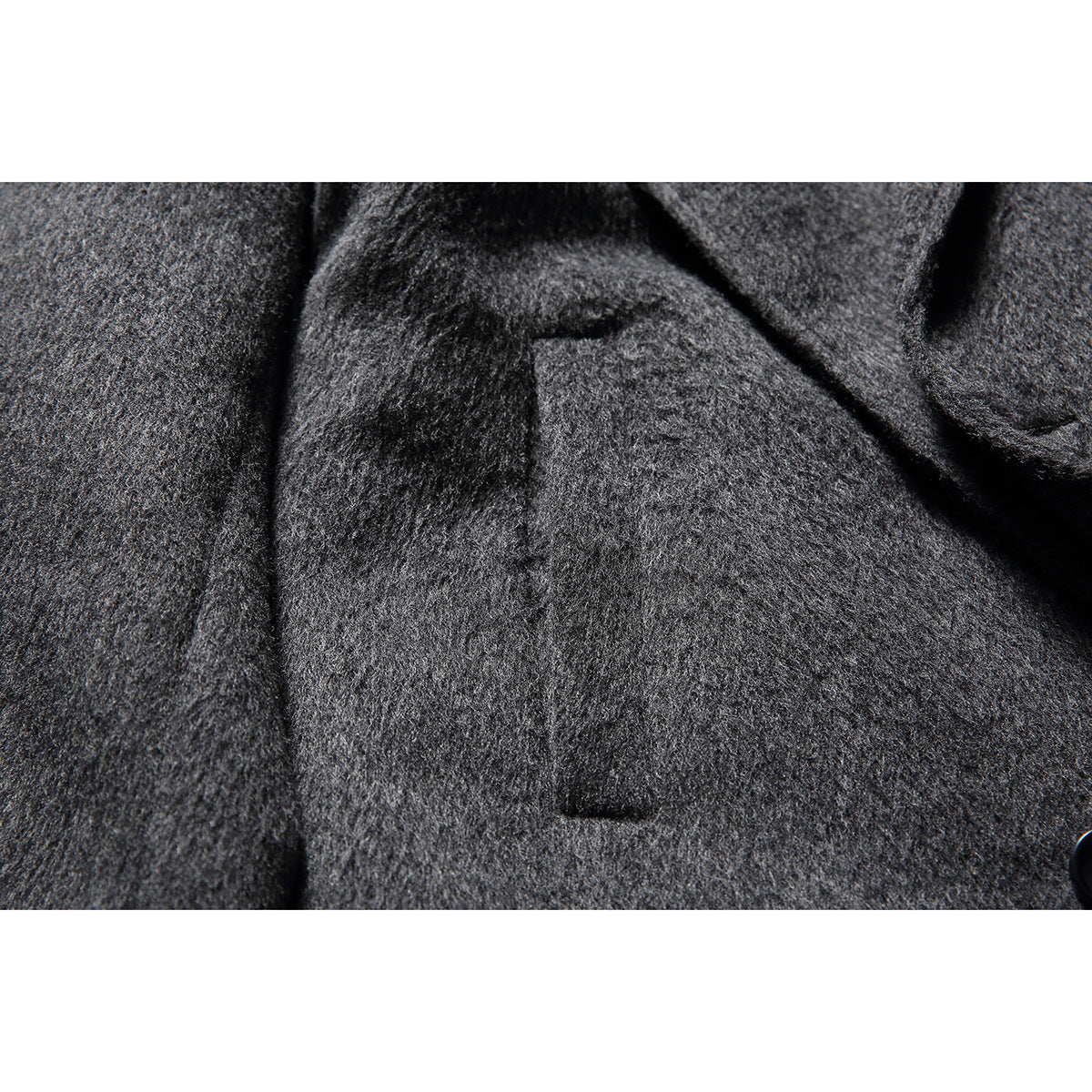Close-up of a welt pocket and textured fabric on the charcoal coat.