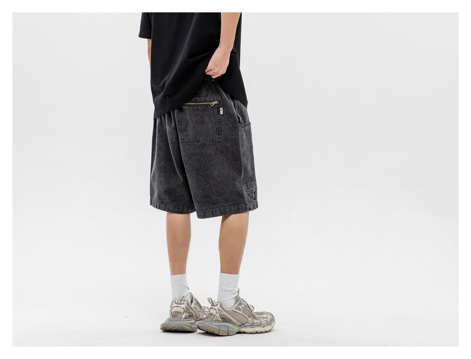 Rear view of a person wearing charcoal utility shorts with a zippered back pocket, white socks, and sneakers.