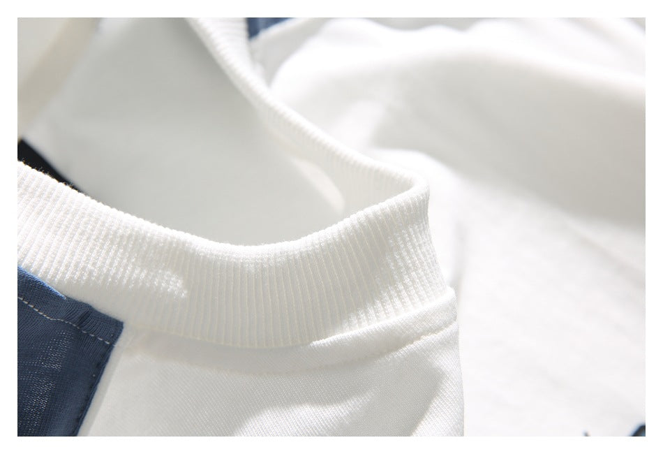 Close-up of the white ribbed crew neckline and blue shoulder panel of a color-block T-shirt.