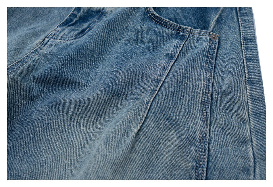 Close-up of faded blue jeans showing a curved pocket opening and small metal rivet.