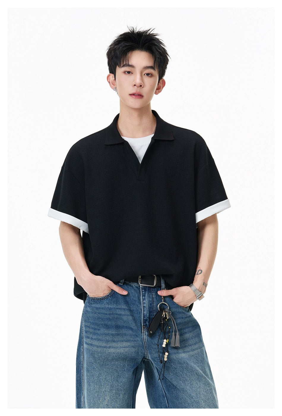 Closer view of a model wearing a black polo with a collar and contrasting white sleeve cuffs.