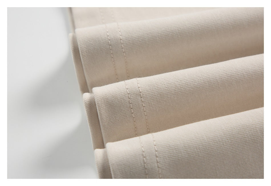 Close-up of beige knit fabric folded to show parallel rows of stitching.