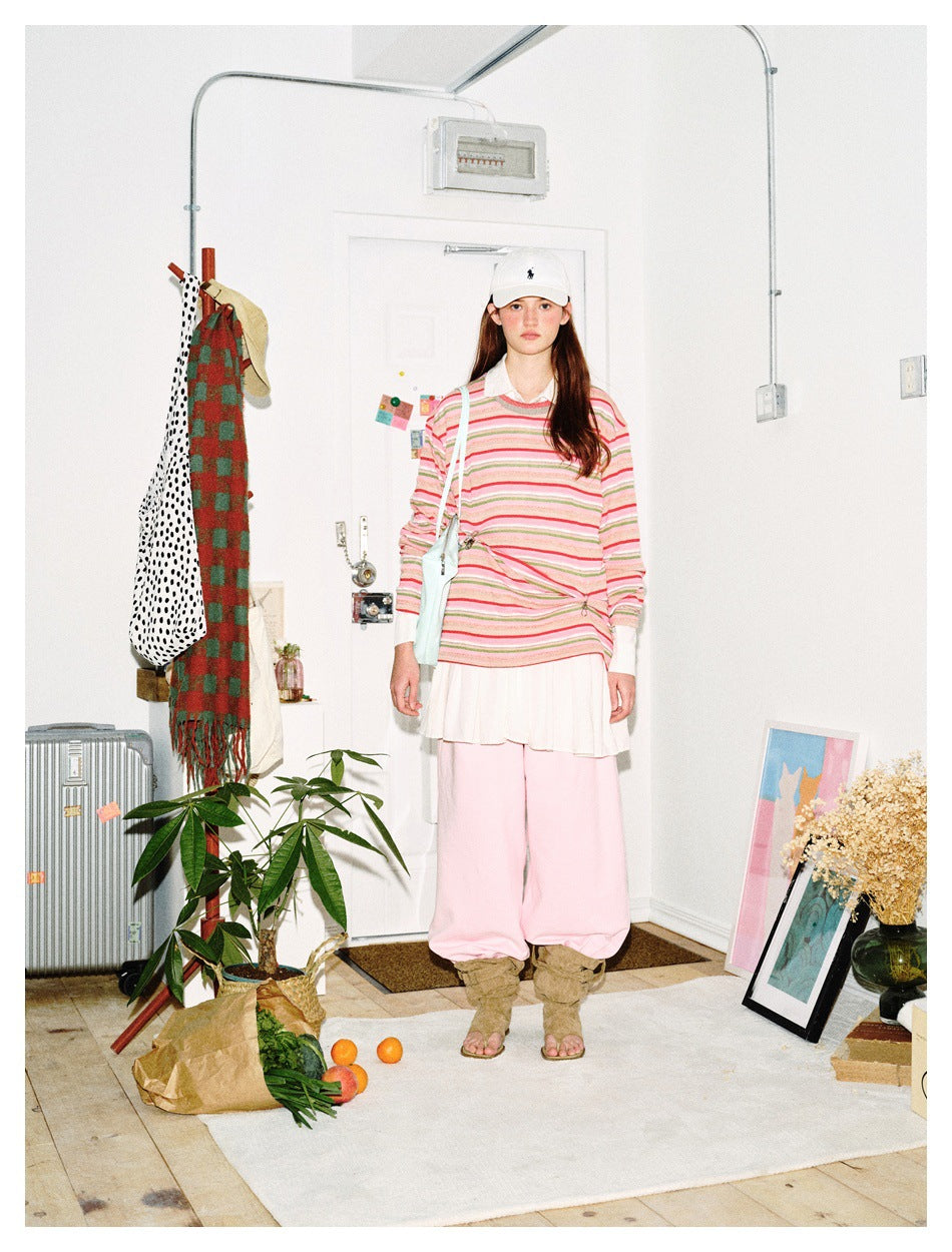 Front view of model wearing a pink, green and white striped long-sleeve top over a white skirt and pink trousers.