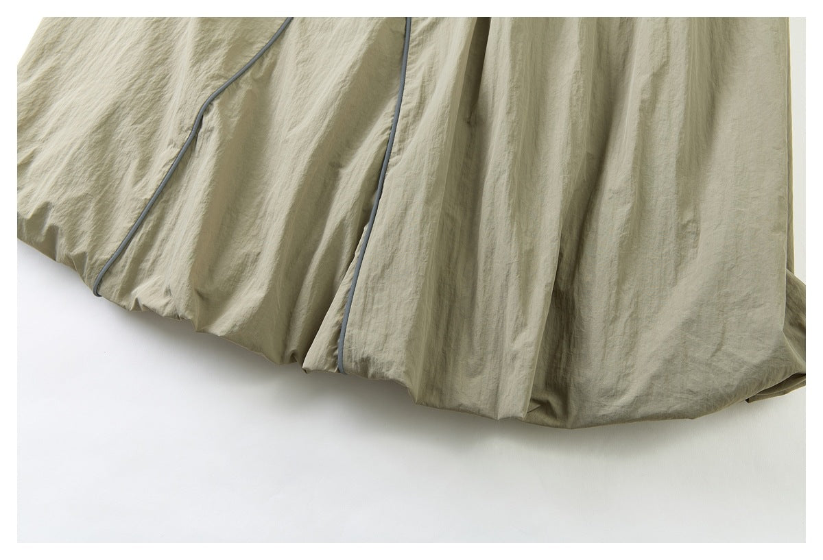 Close-up of the khaki shorts' gathered hem with narrow dark piping.