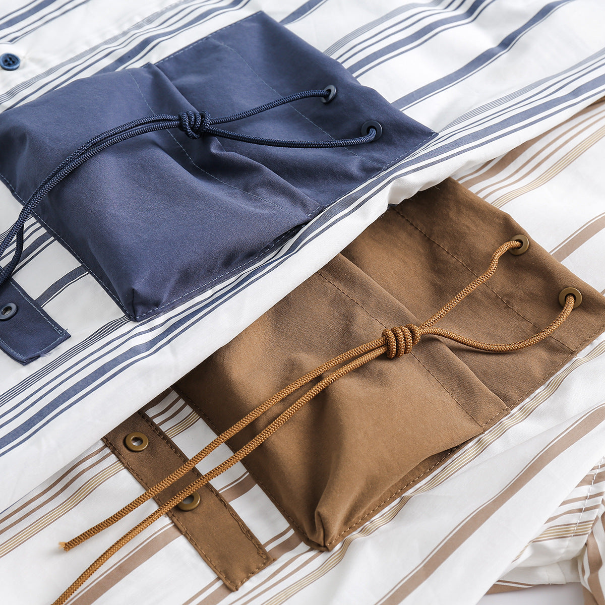 Close-up of navy and tan drawstring pocket details on white shirts with matching stripes.