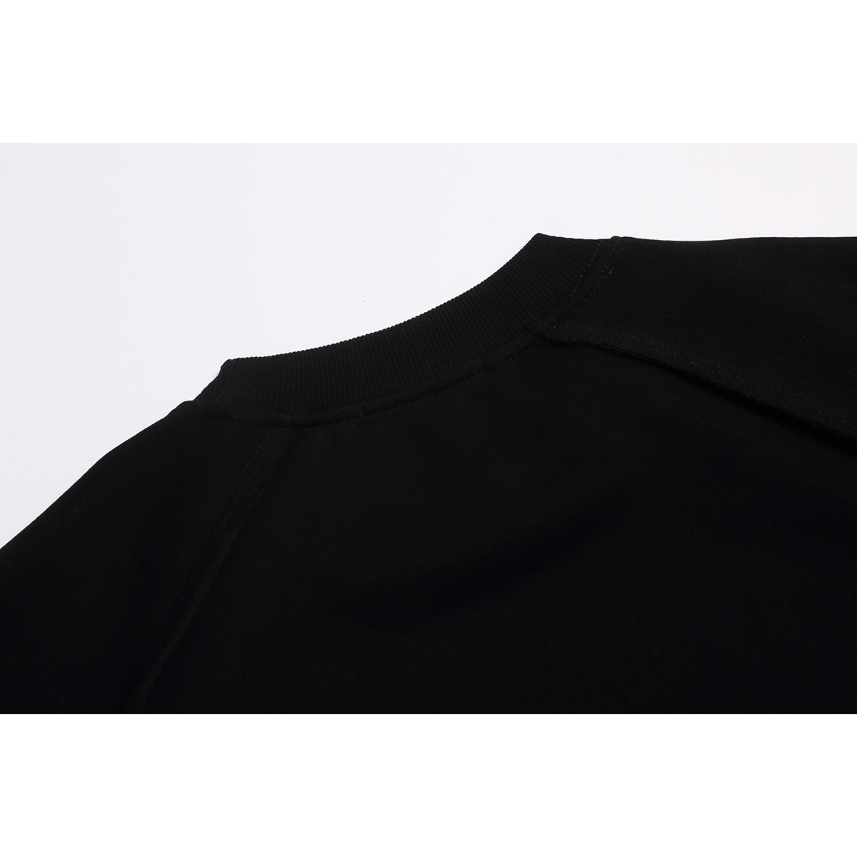 Close-up of the back neckline and shoulder seams of a black sweatshirt.