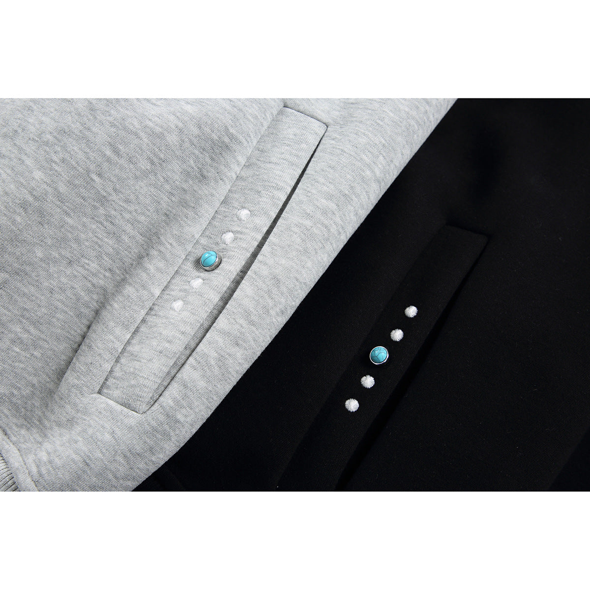 Close-up of gray and black hoodie pocket openings, each decorated with a turquoise stud and small white accents.