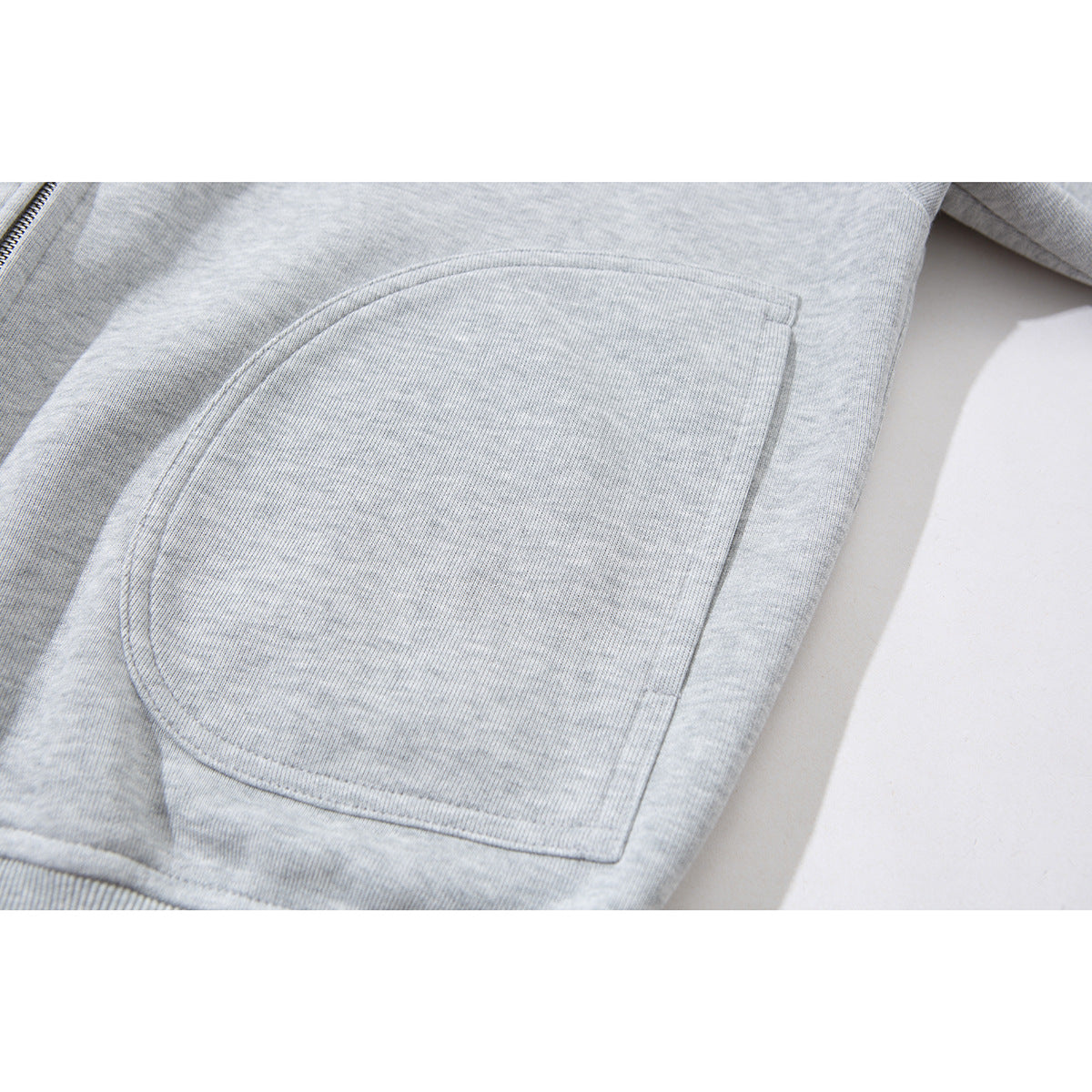 Close-up of a large curved patch pocket on a light gray zip-up jacket.