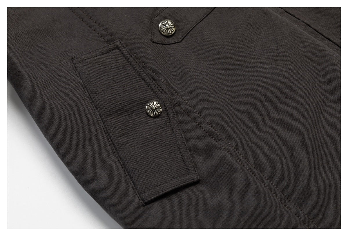 Close-up of a charcoal garment showing stitched panels and two decorative silver floral buttons.