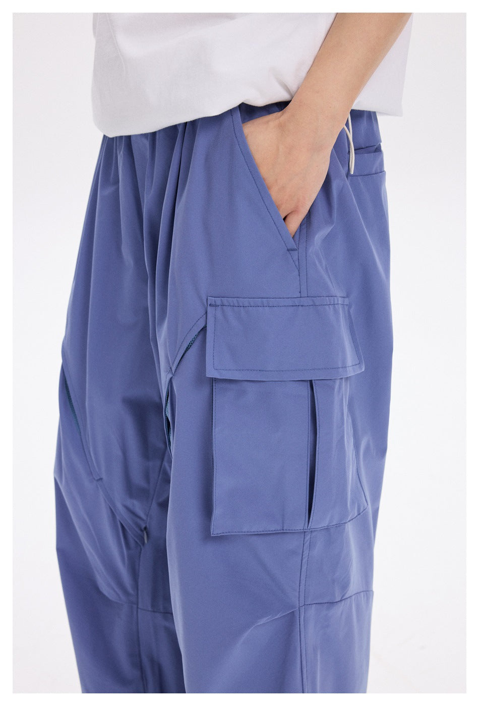 Close view of periwinkle cargo pants showing the side flap pocket, hand pocket, and drawcord waistband.