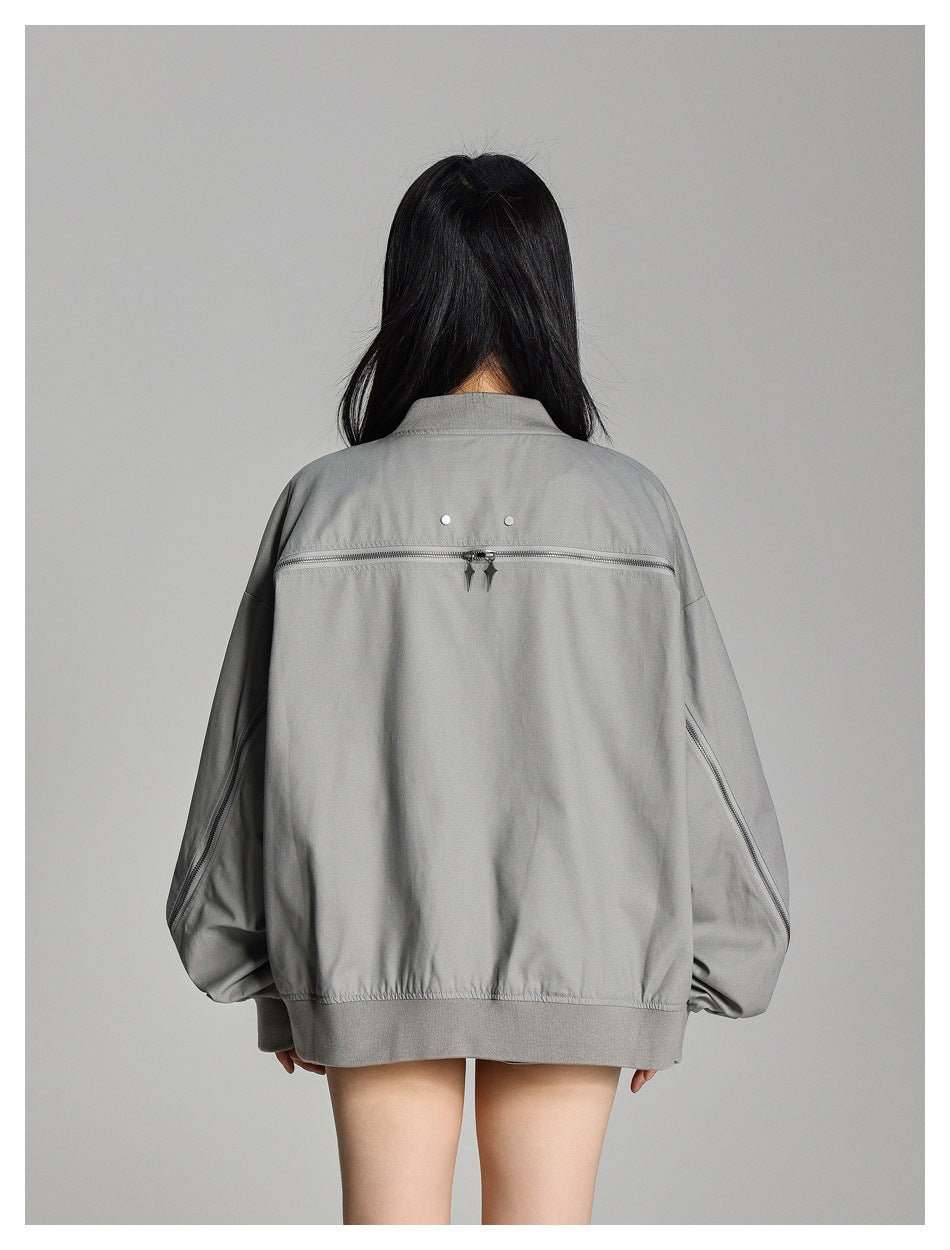 Back view of a model wearing an oversized gray zip-up jacket with a horizontal back zipper and zippered sleeves.