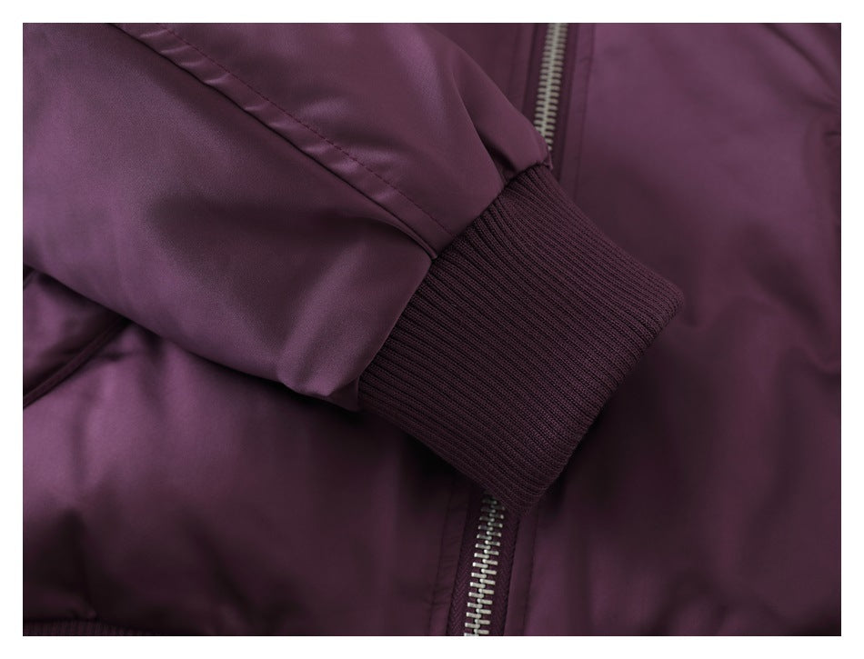 Close-up of a plum-purple jacket sleeve with a dark rib-knit cuff beside the silver zipper.