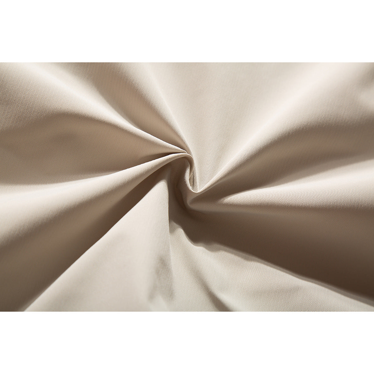 Close-up of light beige jacket fabric gathered into folds, showing its fine surface texture.