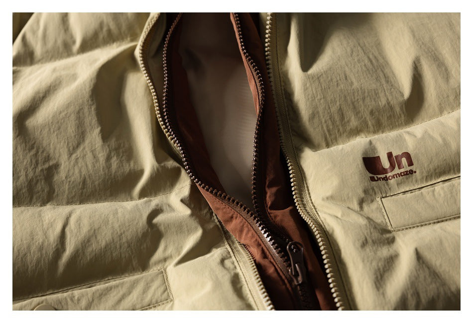 Close-up of an open khaki jacket with rust-colored lining, zipper hardware, and chest pocket.