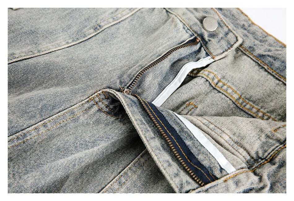 Close-up of the light-wash denim button and partially unzipped fly.