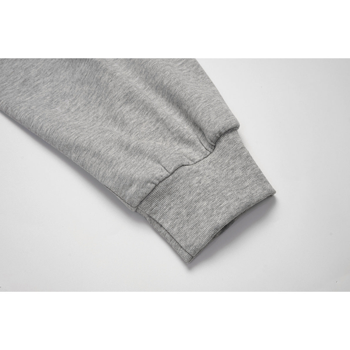 Close-up of a heather gray sweatshirt sleeve ending in a wide ribbed cuff.