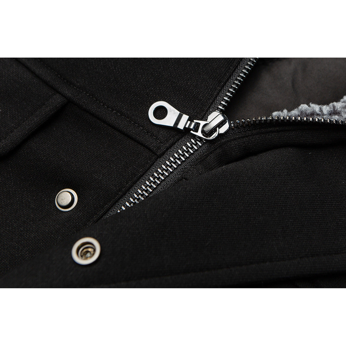 Close-up of a silver zipper and snap fasteners on a black jacket, with gray lining visible.