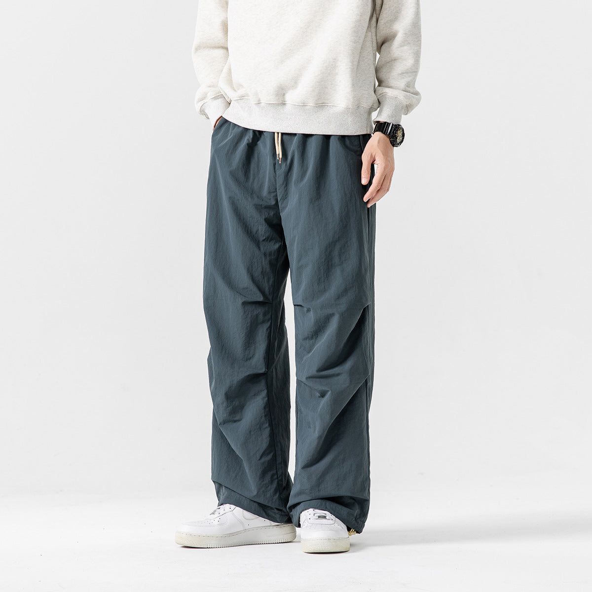 Model wearing loose dark teal drawstring pants with a relaxed fit and wide legs.
