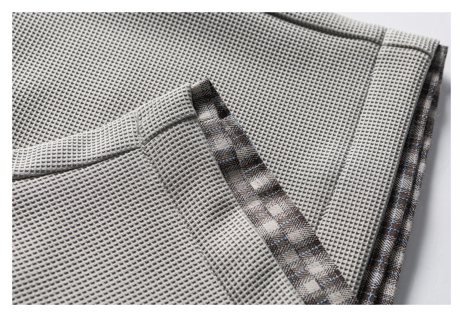 Close-up of gray waffle-textured shorts with brown plaid trim along a seam.