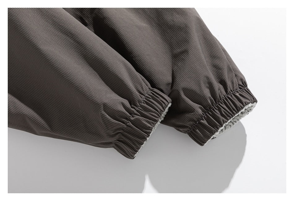 Close-up of a dark gray garment sleeve with gathered elastic cuffs and a glimpse of light lining.