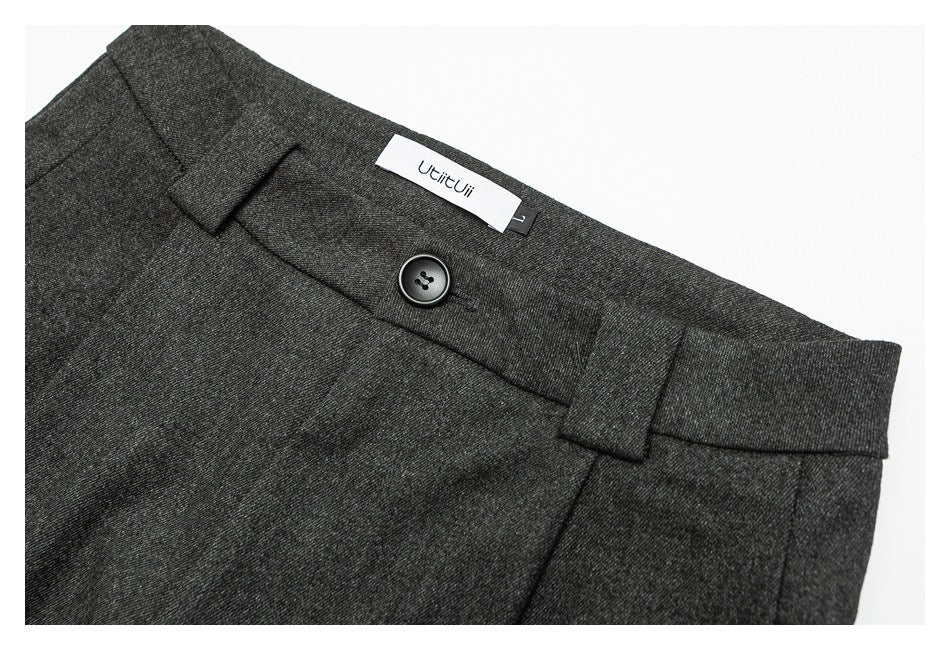 Close-up of charcoal gray trousers showing the waistband button, belt loops, and sewn-in brand label.