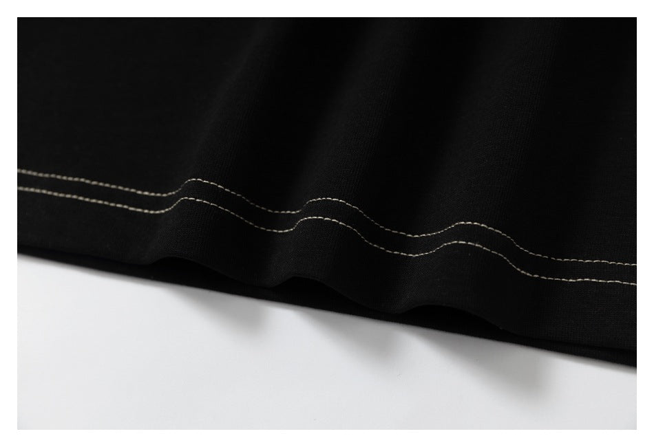 Close-up of the black T-shirt hem with wavy double rows of contrasting stitching.