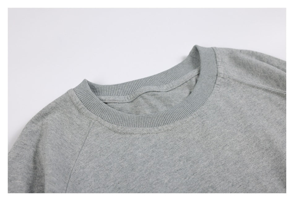 Close-up of a light gray sweatshirt's ribbed crew neckline and shoulder seam.