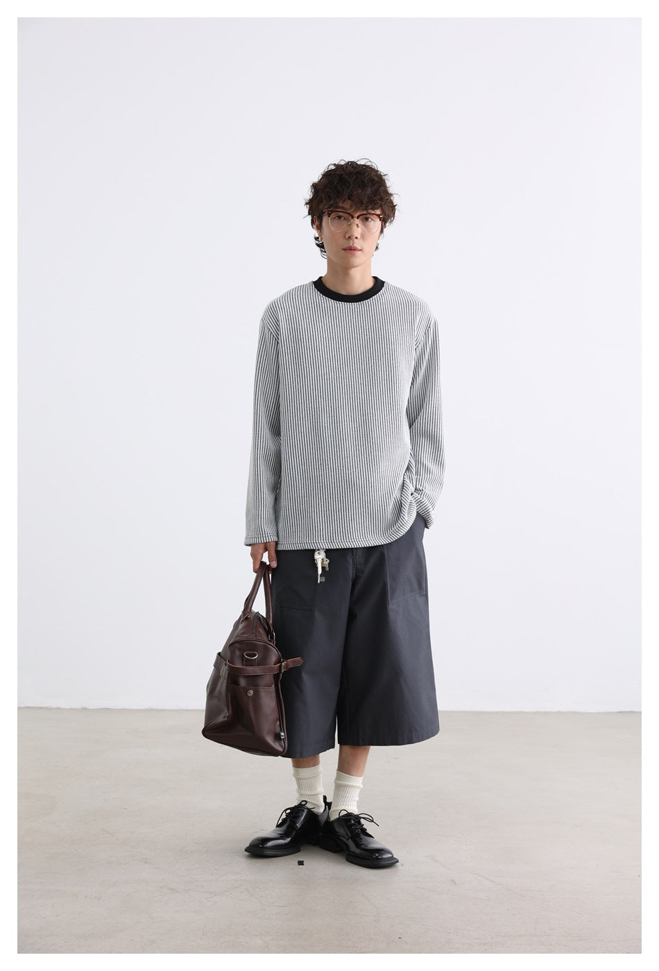 Full-length view of a model wearing a gray-and-white striped long-sleeve shirt with a black crew neck.