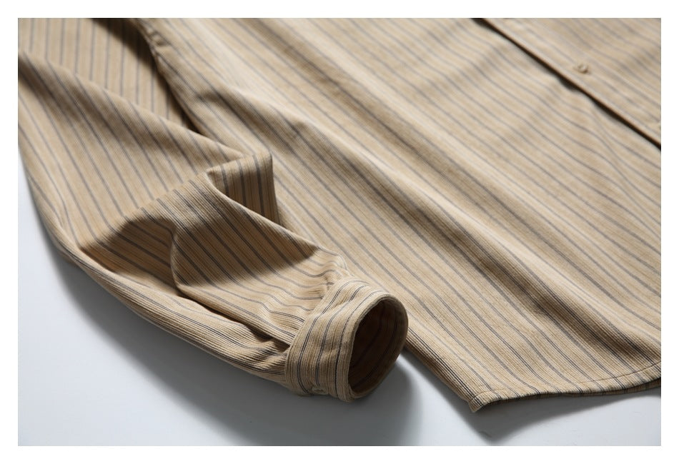 Close-up of the sleeve, cuff and front of a beige shirt with fine dark vertical stripes.