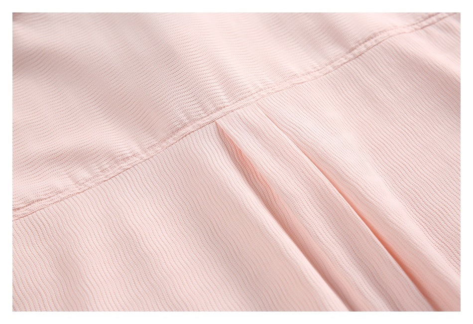 Close-up of a stitched seam and folded fabric detail on a pale pink ribbed garment.