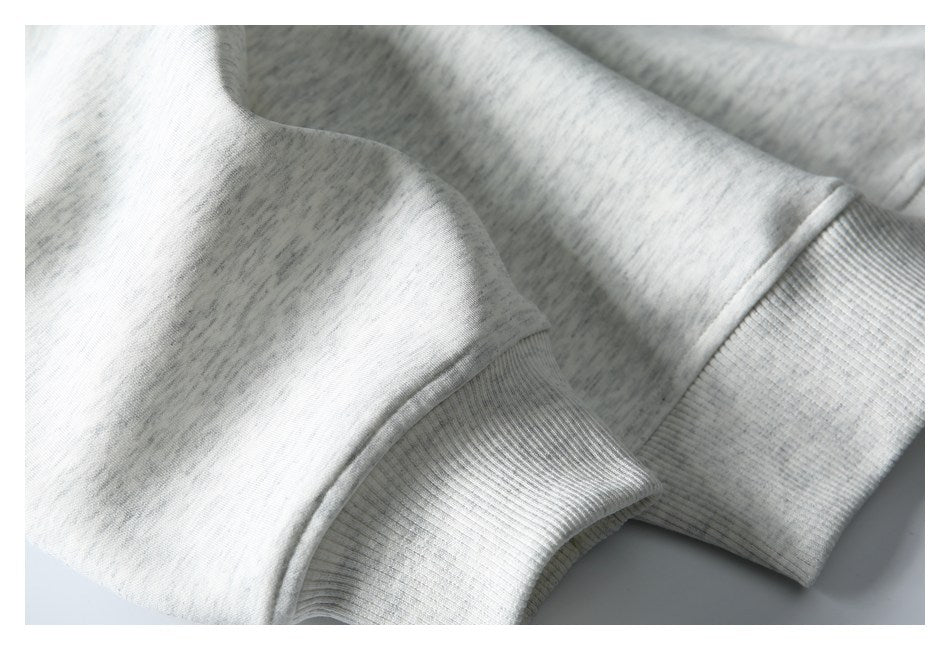 Close-up of a light gray heathered sleeve ending in a ribbed cuff.
