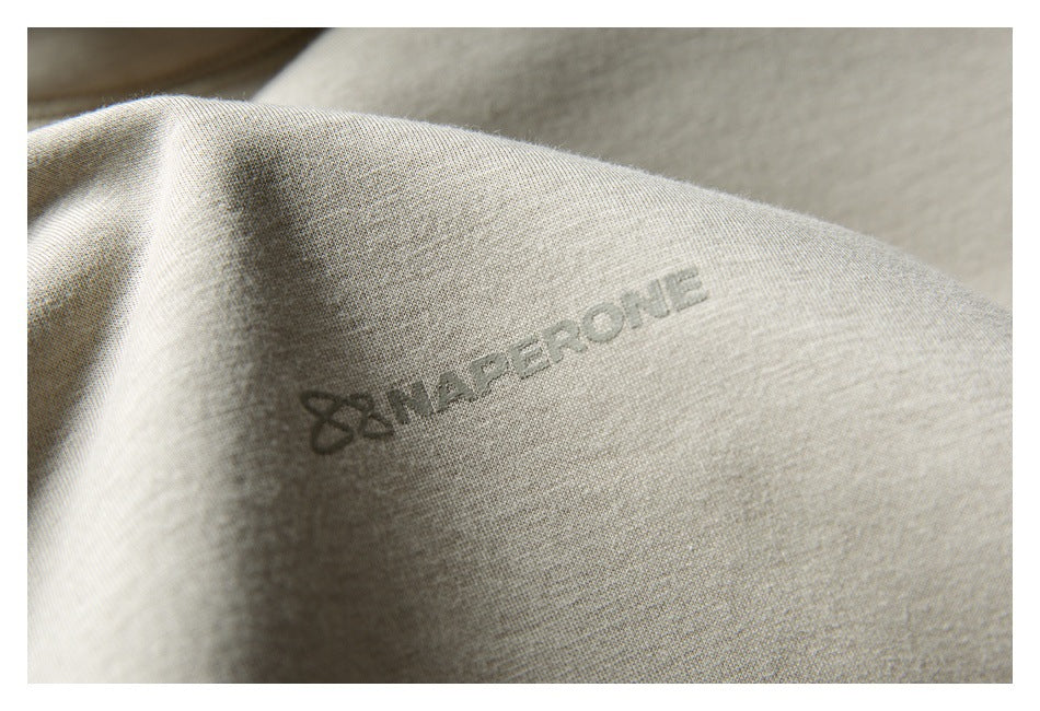 Close-up of a small dark logo printed on light beige sweatshirt fabric.