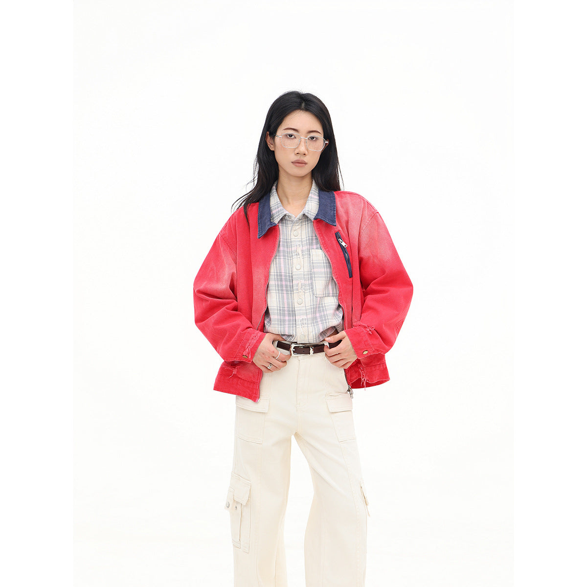 Closer view of a model wearing a coral-red zip jacket with a dark blue collar over a plaid shirt.