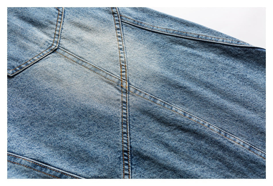 Close-up of faded blue denim panels and intersecting orange topstitched seams.