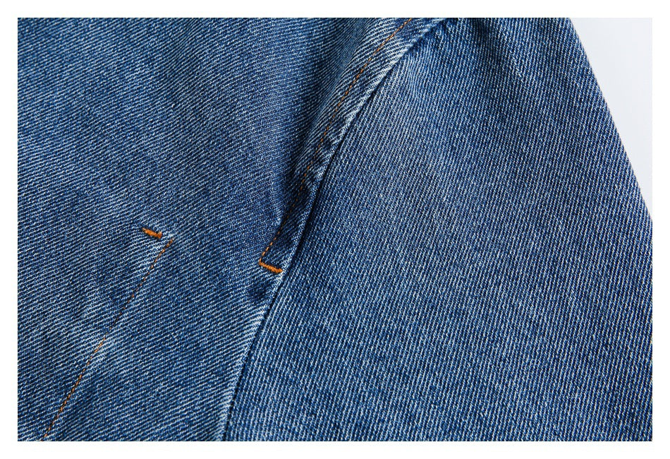 Close-up of blue denim with orange topstitching and a curved seam.