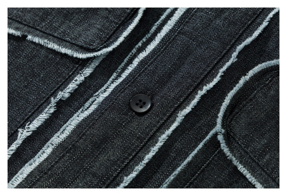 Close-up of a black button and frayed pale seam edges on dark denim.