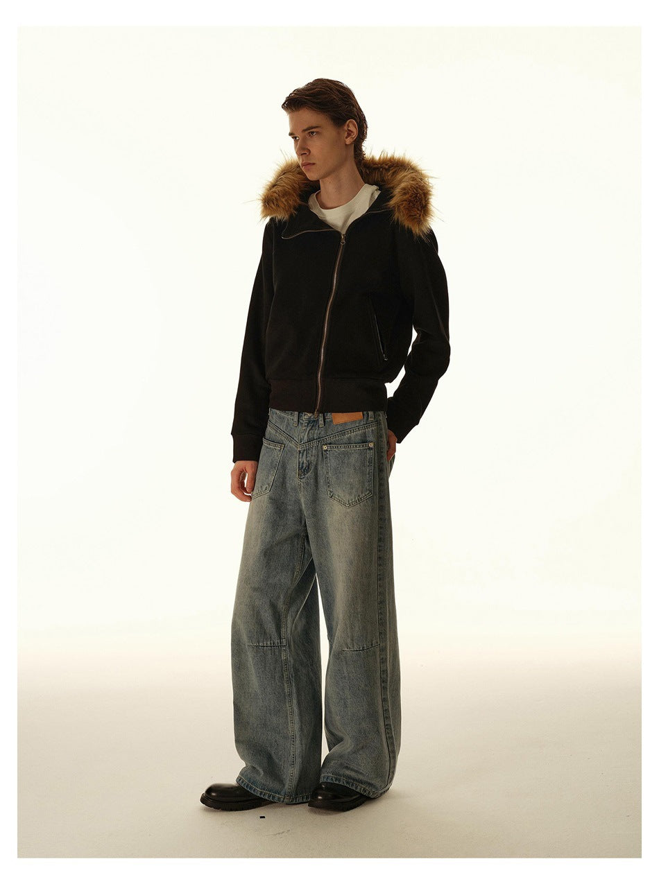 Three-quarter view of a model wearing a black fur-trimmed hooded zip jacket and loose blue jeans.