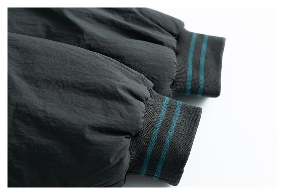 Close-up of two charcoal ribbed cuffs with teal stripes on a dark garment.