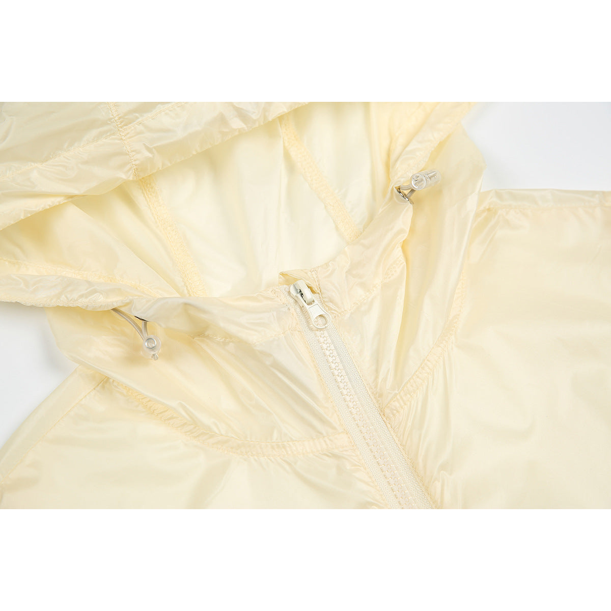 Close-up of a pale cream jacket's lightweight-looking fabric, zipper, seams, and hood adjustment toggle.