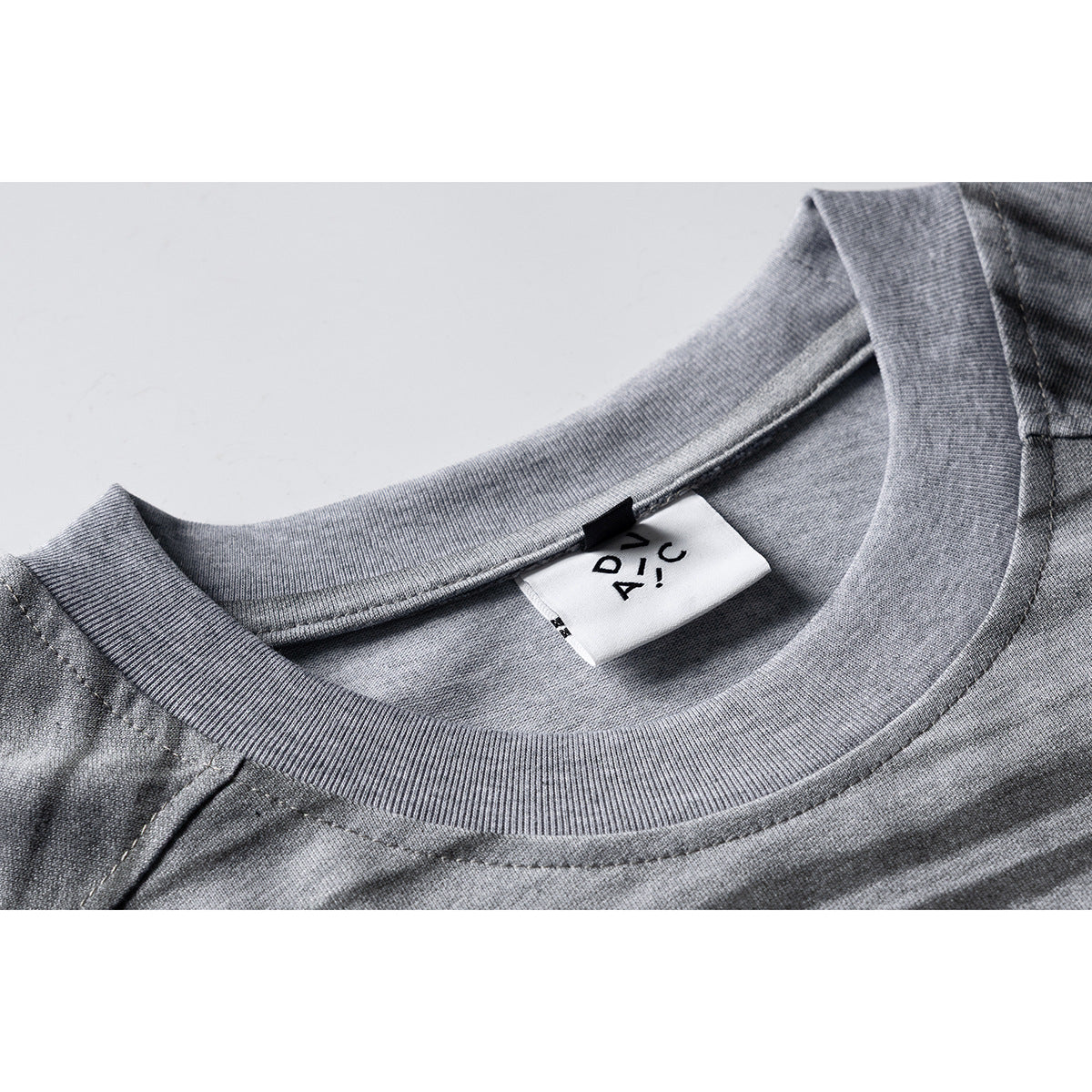 Close-up of a gray striped T-shirt neckline and ribbed collar, with a white sewn-in label.