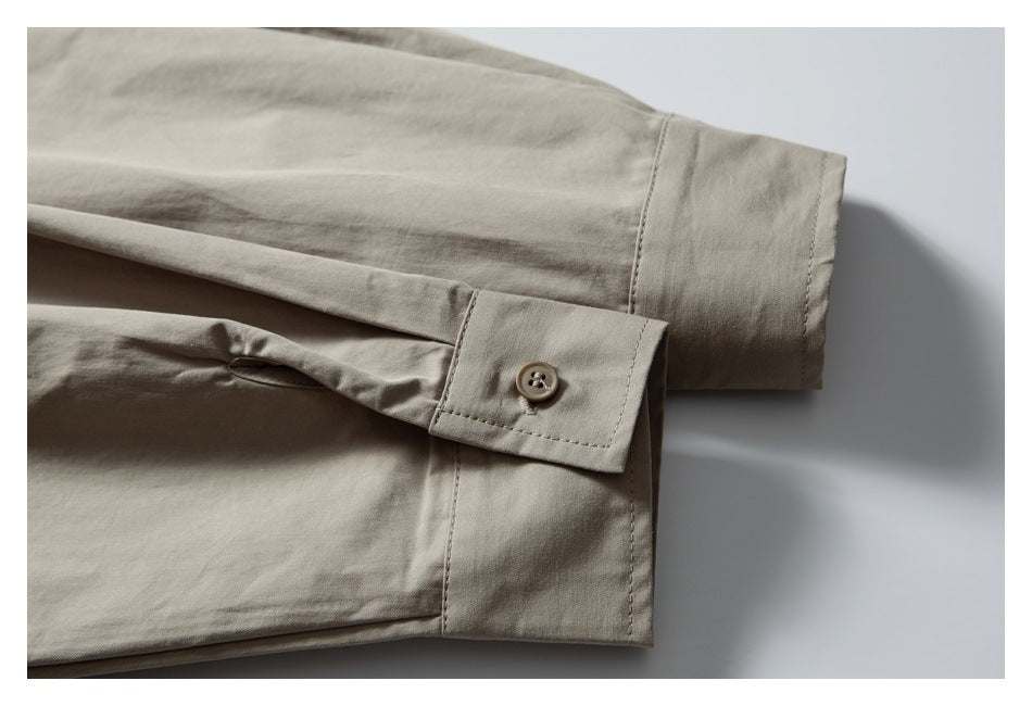 Close-up of a beige shirt cuff with a button closure and stitched sleeve hem.