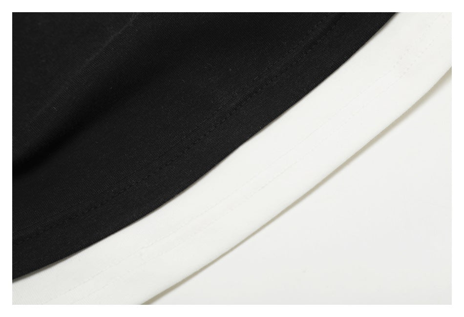 Close-up of black and white garment fabric meeting at a curved, stitched edge.