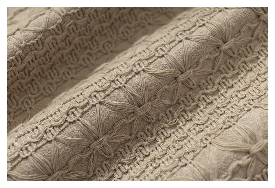 Macro view of beige raised floral stitching and textured fabric in diagonal bands.